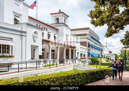 Hot Springs, USA - June 4, 2019: Historical Ozark Baths Spa white architecture bath house with American flag and dome by magnolia southern tree in cit Stock Photo