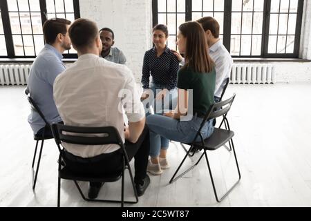 People sitting in circle participating at group therapy session Stock Photo