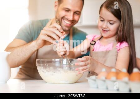 Father And Daughter Making Dough For Pancakes In Kitchen Indoor Stock Photo