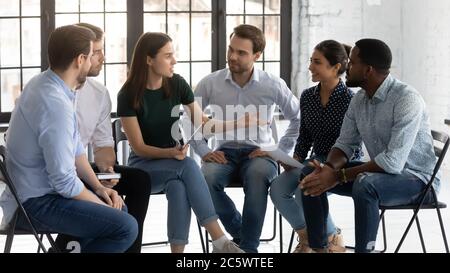 Six employees sit on chairs discussing taking part in seminar Stock Photo