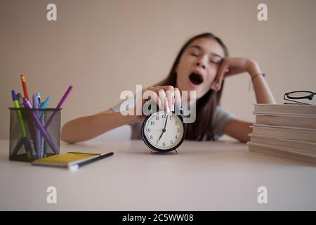 Teenage girl is yawning from studying and doing her homework. Tired and desperate student. Education, children and school concept Stock Photo
