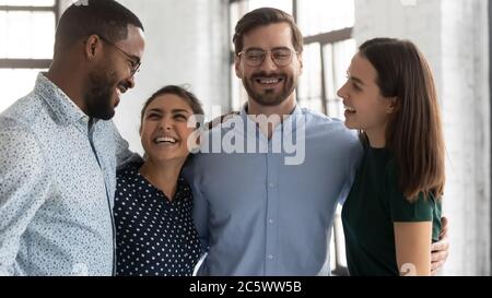 Friends colleagues hugging laughing enjoy conversation celebrate common win together Stock Photo
