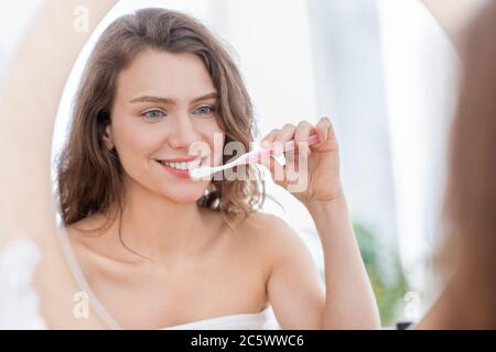 Young woman brushing teeth in bathroom at home Stock Photo