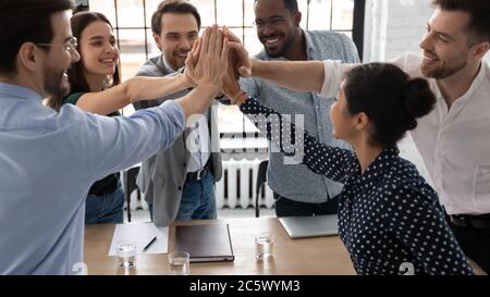 Excited multiethnic staff members giving high five sharing success Stock Photo