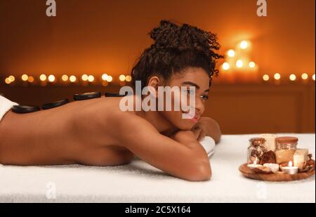 Peaceful african woman enjoying healing massage at spa Stock Photo