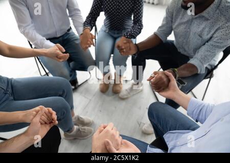 People sitting in circle holding hands involved at group therapy Stock Photo