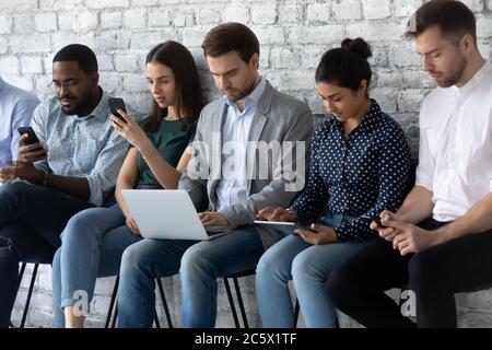 Multiracial applicants focused in gadgets while await for job interview Stock Photo