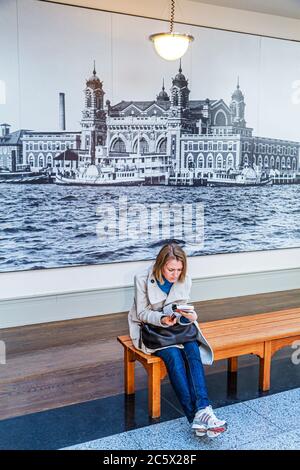 New York City,NYC NY Statue of Liberty National Monument,Ellis Island Immigration Museum,historic site,Great Hall,bench,vintage photograph,woman femal Stock Photo