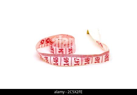 Red tailors centimeter on white background. Measuring tape closeup photo. Tailoring service or slimming diet concept. Summer vacation beach body conce Stock Photo