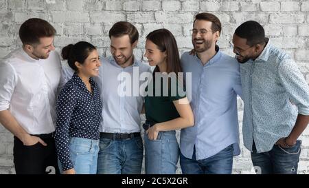 Multiracial millennial men and women standing indoor enjoy friendly communication Stock Photo