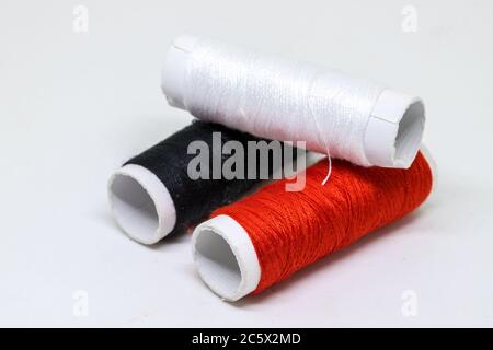 Thread spool pile on white background. Basic color of thread: red, white, black. Cotton thread spool perspective view. Tailoring service or sewing equ Stock Photo