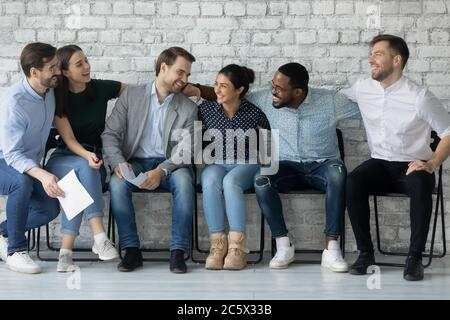 Multiethnic employees sit on chairs in office corridor enjoy communication Stock Photo