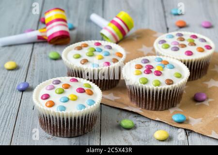 Chocolate cupcakes glazed with smarties, wooden background Stock Photo
