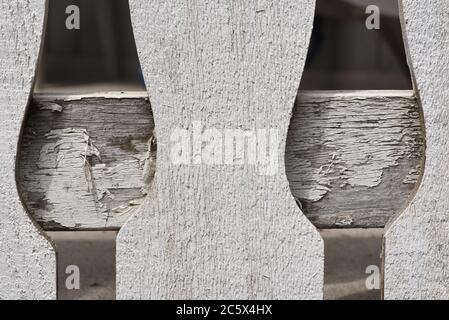 Paint flakes off a board that is part of a porch deck reailing Stock Photo