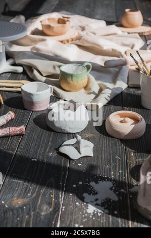 Art of pottery. Still life of pottery making tools, brushes and different ceramic vases and bowls in clay studio Stock Photo