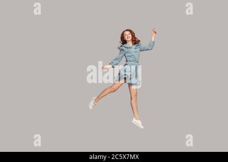 Happy delicate girl in vintage ruffle dress levitating with ballet dance move, hovering in mid-air and smiling joyfully, jumping trampoline, flying up Stock Photo
