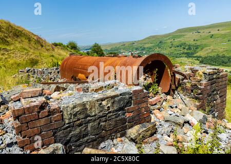 Rusting remains of an old, Victorian era boiler and lifting engine house abandoned on a hillside overlooking the Welsh town of Ebbw Vale Stock Photo