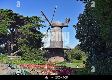 The North Dutch Windmill surrounded by Queen Wilhelmina Garden with flowers, trees and blue sky in the Golden Gate Park, San Francisco, California. Stock Photo