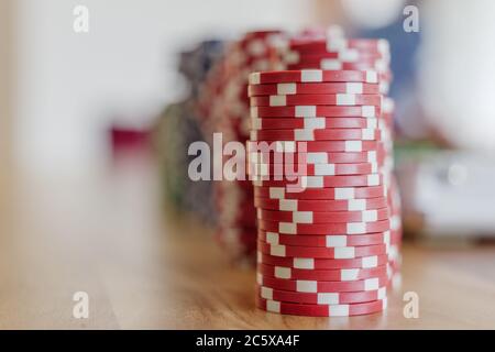 Selected focus at stacks of red plastic poker chips on wooden table and defocus background of blue and green ones. Stock Photo