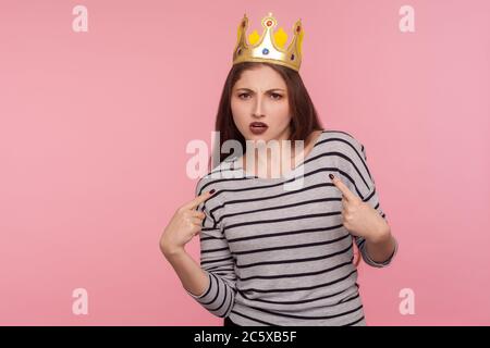 I'm boss! Portrait of selfish egoistic woman with golden crown on head pointing herself and looking with arrogance, declaring her authority, leadershi Stock Photo