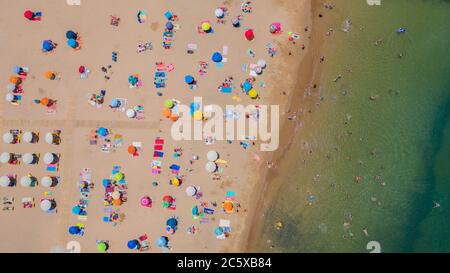 Aerial view of sandy beach with tourists swimming in beautiful clear sea water in Madeira island. Stock Photo