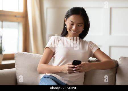 Smiling young vietnamese woman using mobile applications. Stock Photo