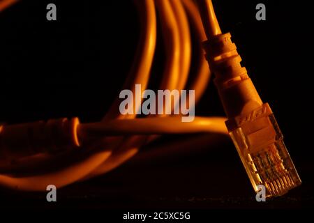 Yellow network cable with rj45 connector on a black background, tecnology and network Stock Photo