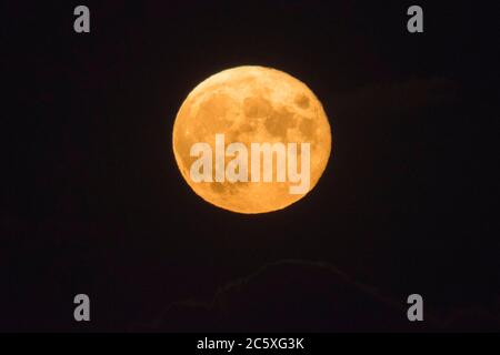 Highcliffe, Dorset, UK.  5th July 2020.  UK Weather. The full Buck Moon glows orange, viewed from Highcliffe in Dorset shortly after moonrise.  Picture Credit: Graham Hunt/Alamy Live News Stock Photo