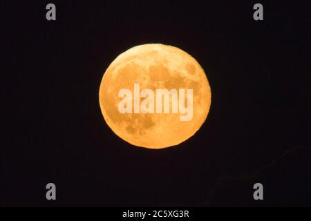 Highcliffe, Dorset, UK.  5th July 2020.  UK Weather. The full Buck Moon glows orange, viewed from Highcliffe in Dorset shortly after moonrise.  Picture Credit: Graham Hunt/Alamy Live News Stock Photo