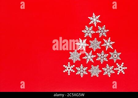 Christmas tree made from white snow flake decorations on red  background with empty copy space for text. New year and christmas postcard. Stock Photo