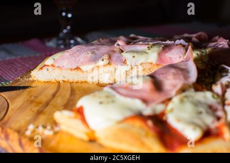 Ham and mozzarella pizza cut on wooden tray Stock Photo