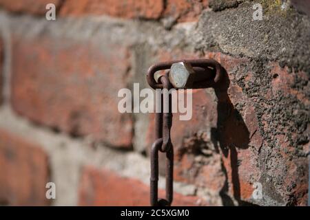 Screw with rusty chain in a brick wall Stock Photo