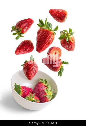 Strawberries flying in white bowl isolated from the background - red and white vertical image Stock Photo