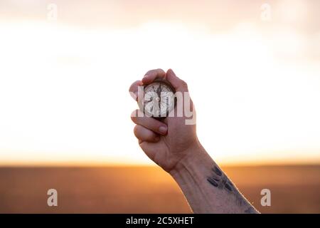 hand holds a compass in flower field Stock Photo