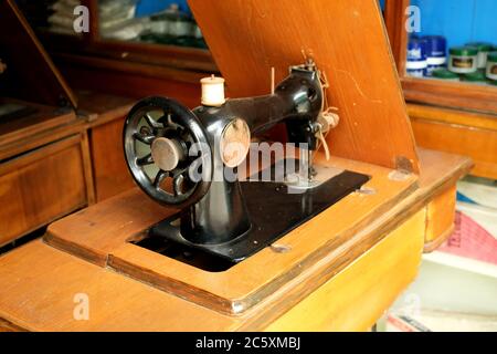 An old model of sewing machine on wood table Stock Photo