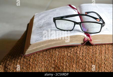 Open bible on a pilllow, with reading glasses on top of it. Copy space. Stock Photo