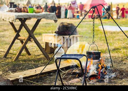 Camping outdoors - tents, equipment and cooking. Cooking at a camping site in nature. The bowler is basking in the fire. Stock Photo