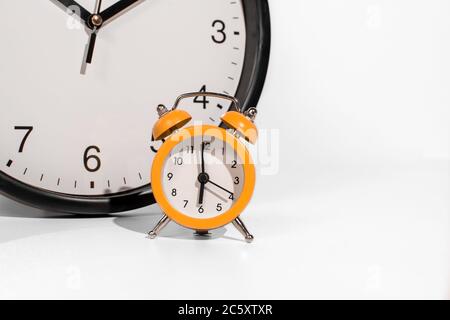 Small orange time clock with bigger clock in background Stock Photo