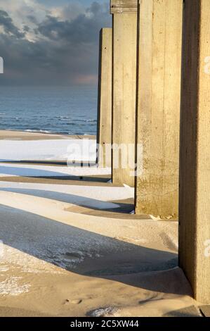 Sunlight through cement walls on a winter beach create a pretty abstract Stock Photo