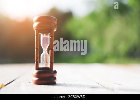 Small hourglass show time is flowing on sand beach texture background. Stock Photo