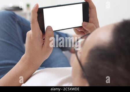 Man plays game on smart phone gesture, empty blank white phone screen mock up template, top view Stock Photo