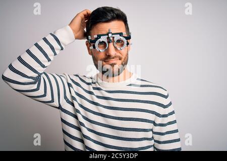 Young handsome man with beard wearing optometry glasses over isolated white background confuse and wonder about question. Uncertain with doubt, thinki Stock Photo