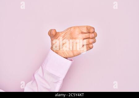 Hand of caucasian young man showing fingers over isolated pink background holding invisible object, empty hand doing clipping and grabbing gesture Stock Photo