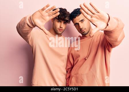 Young gay couple wearing casual clothes doing frame using hands palms and fingers, camera perspective Stock Photo