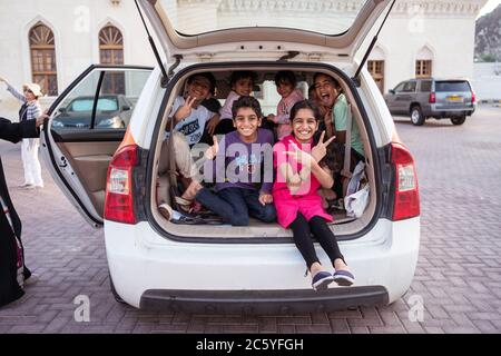 Muscat / Oman - February 10, 2020: group of cheerful children sitting in the trunk of a small car Stock Photo