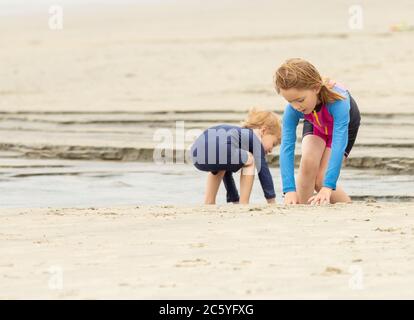 Two children, a young boy and a girl, playing on a sandy beach