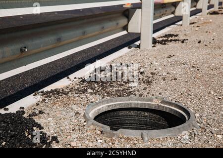 An open sewer hatch that poses a danger to people who walk along the city street. No manhole covers. Repair work Stock Photo