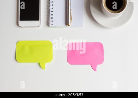 top view of white office desk, two colored stickers for notes, smartphone, notebook with metallic pen and cup of black coffee, business mockup Stock Photo