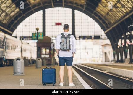 man at railway station waiting for late train with bag Stock Photo