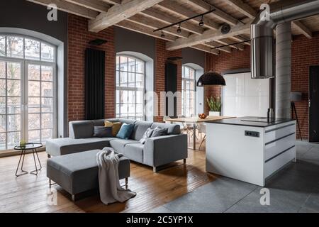 Loft interior with wooden ceiling, corner sofa and kitchen island Stock Photo
